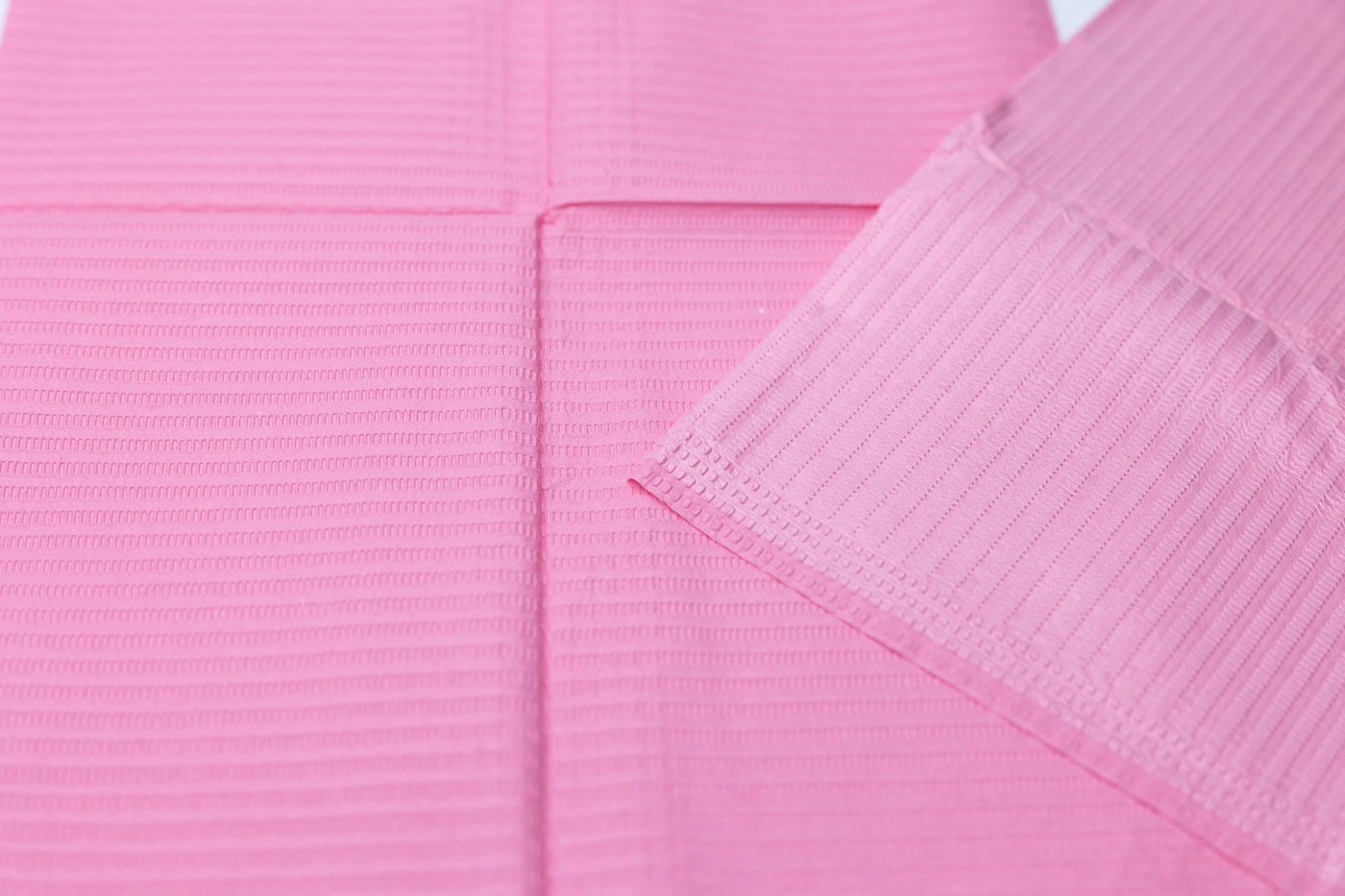 A pair of pink towels on a white surface, ideal for PMU procedures or as Espoir Studios DISPOSABLE DENTAL BIBS (125 pieces).