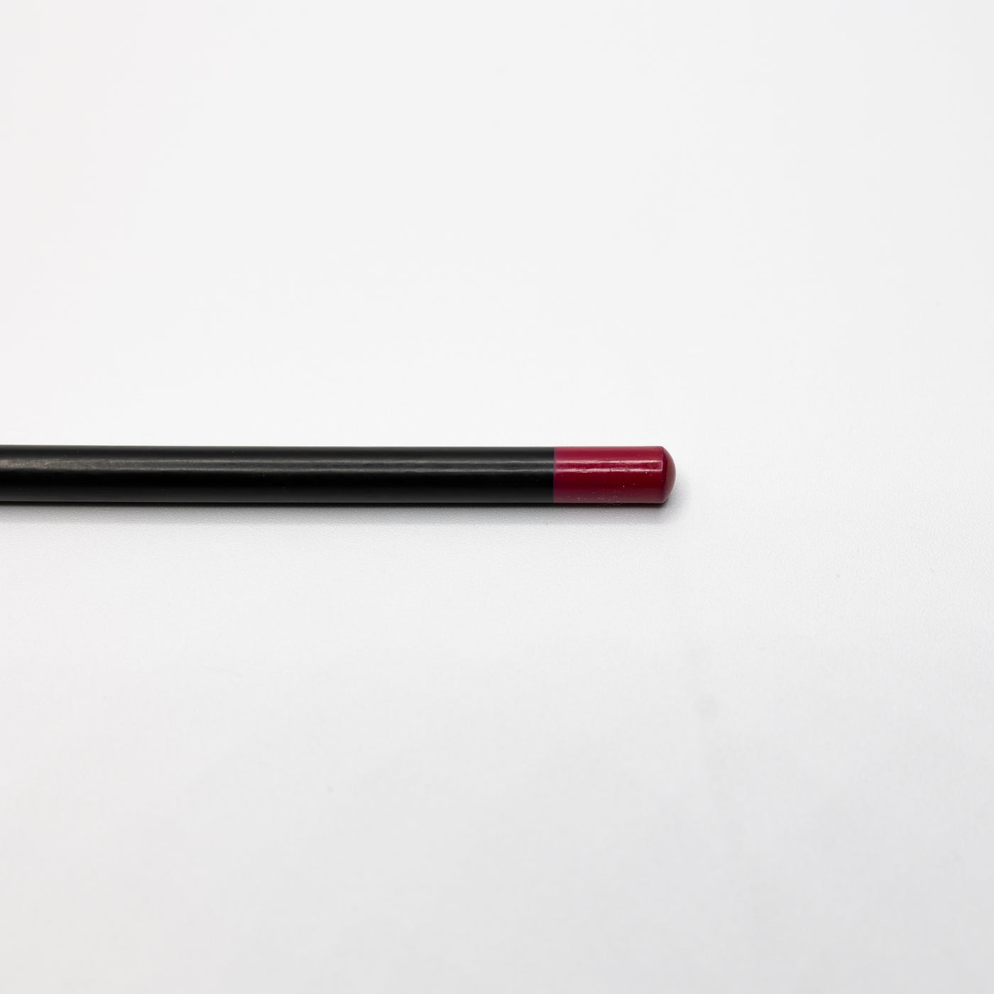 A black pencil with a red eraser end, reminiscent of Espoir Studios' RED LIP LINER PREDRAW PENCIL, lies horizontally on a plain white surface.