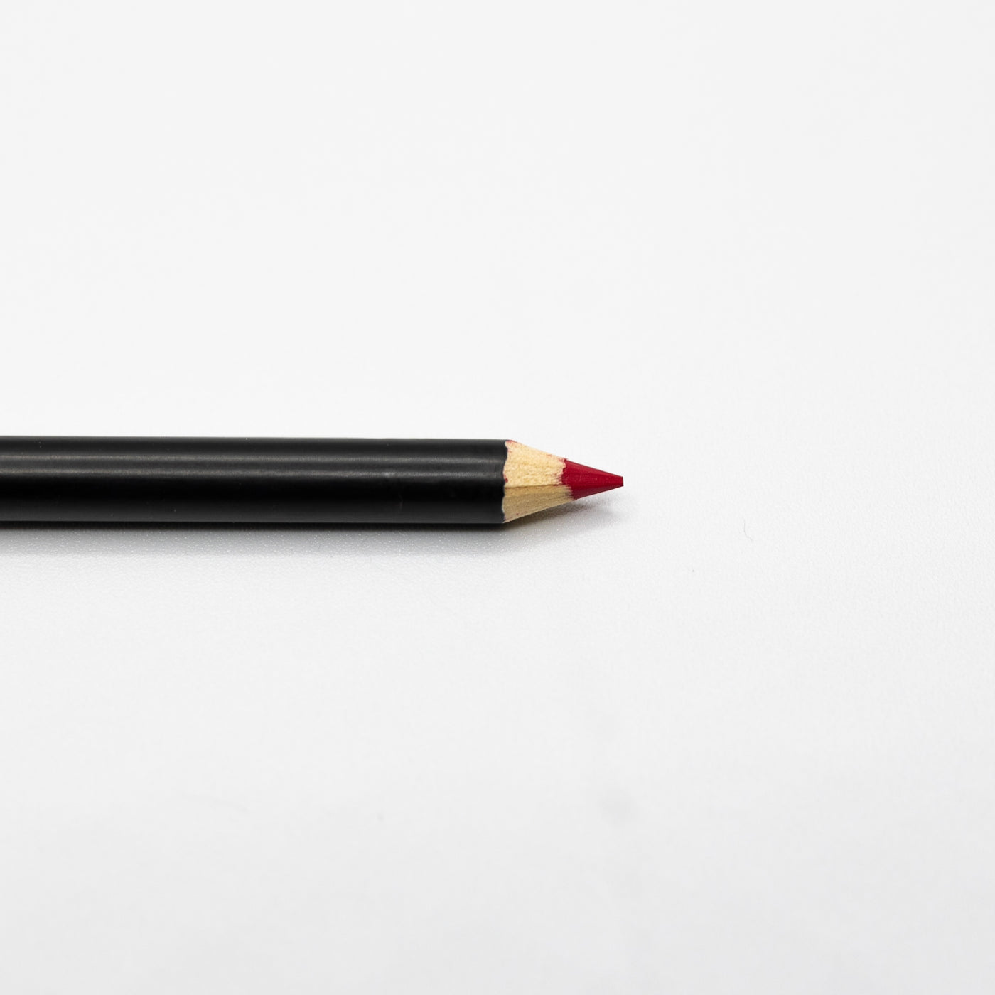 An Espoir Studios RED LIP LINER PREDRAW PENCIL with a sharpened red tip, perfect for lip mapping, lies on a white surface.