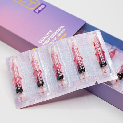 Five pink syringe-like cartridges rest in a sealed plastic tray, partially inside an open box labeled "Quality Professional for Artist." These Dragonhawk MAST PRO SE UNIVERSAL NEEDLE CARTRIDGE (3RL) needles are a special edition designed to meet the needs of discerning professionals.